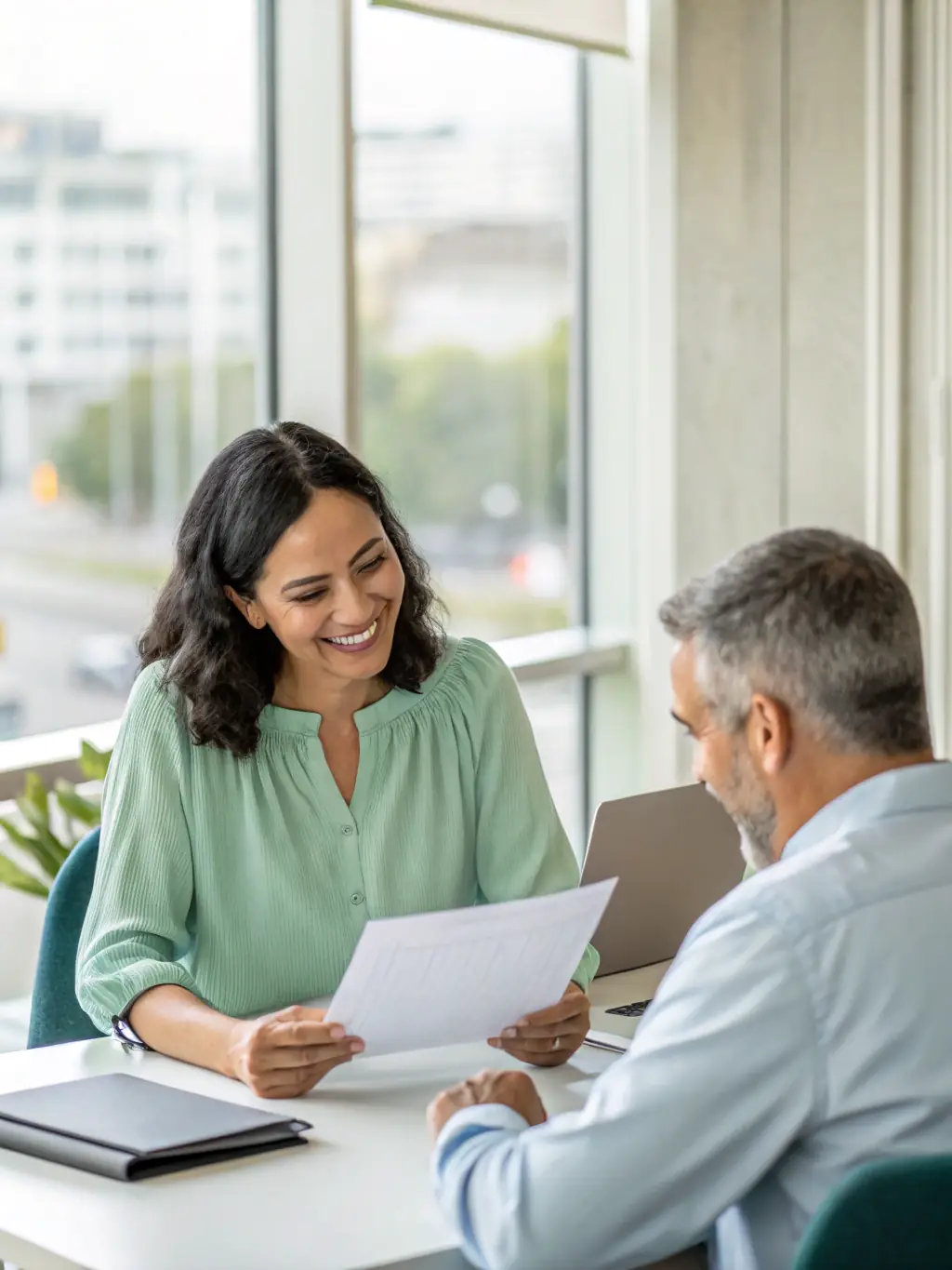 A person sitting at a desk, reviewing financial documents with a coach, representing the Personal Financial Coaching program.