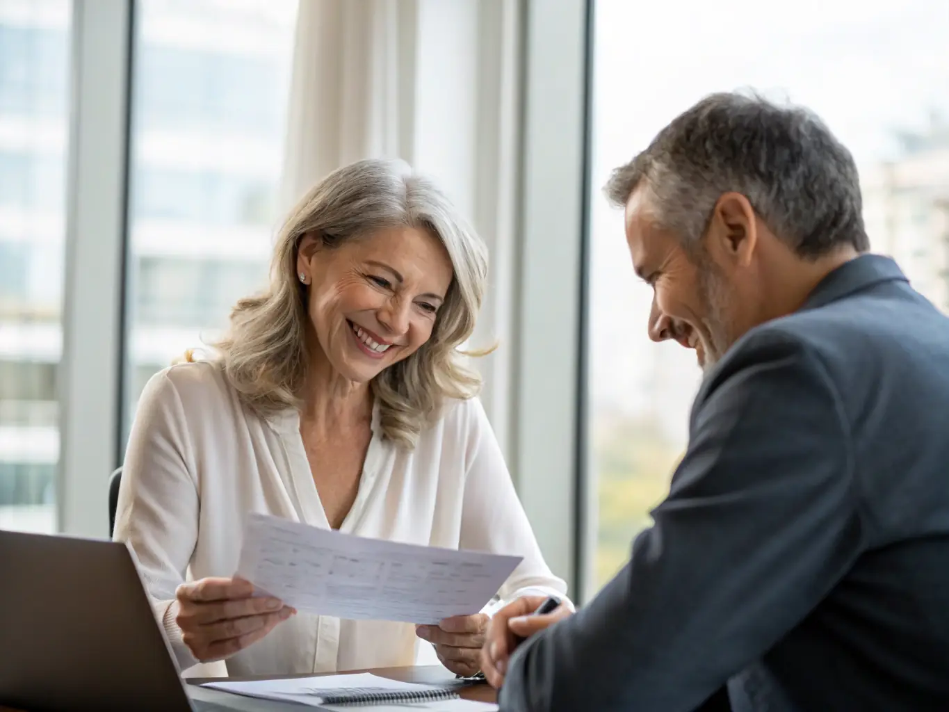 An image of a business owner reviewing financial documents with a coach in a modern office environment, representing financial planning for entrepreneurs.